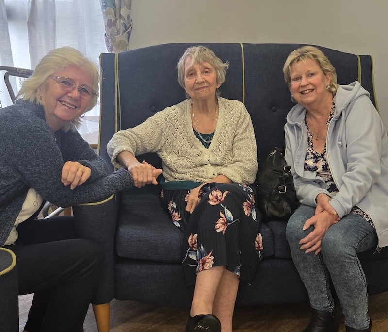 3 female residents sat on the sofa together smiling